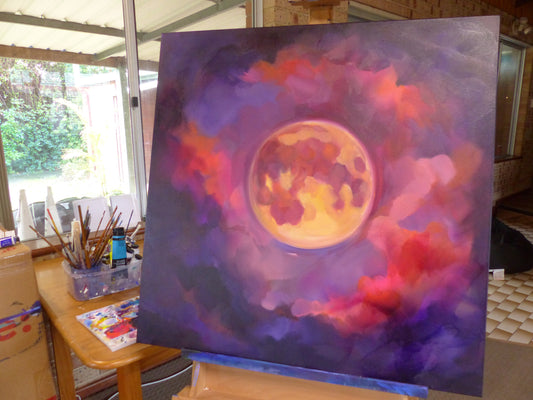 colourful glow in the dark moon painting with red, yellow and pink clouds.