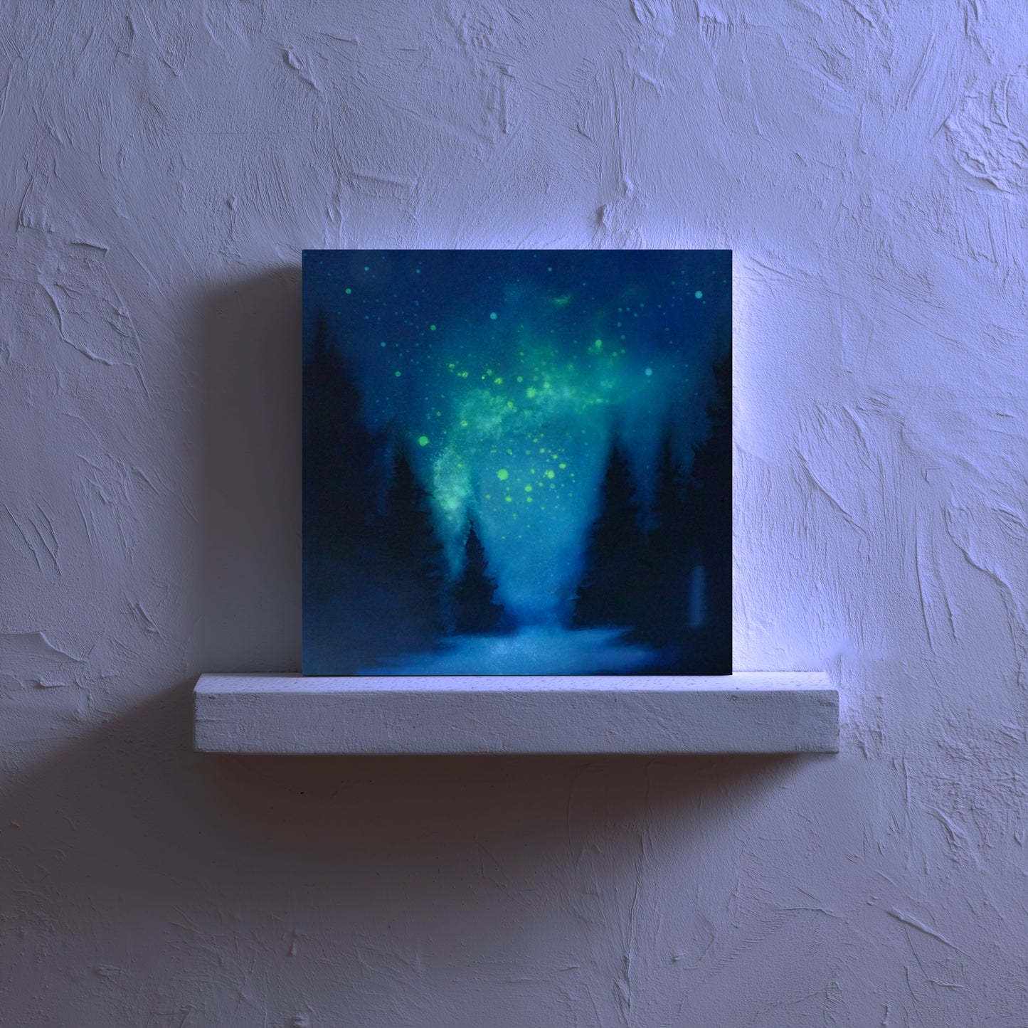 painting of a forest under a glow ing starry night sky on a white ledge against a textured wall.