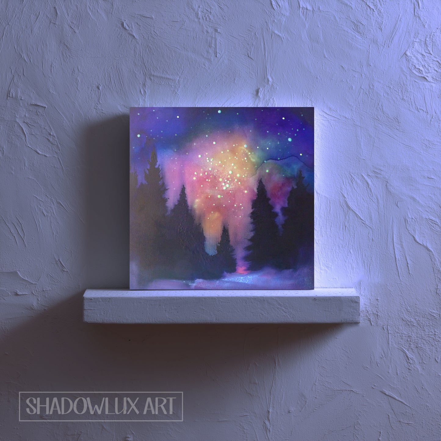 Canvas glow painting of a forest under a colorful pink night sky on a white ledge against a textured wall.