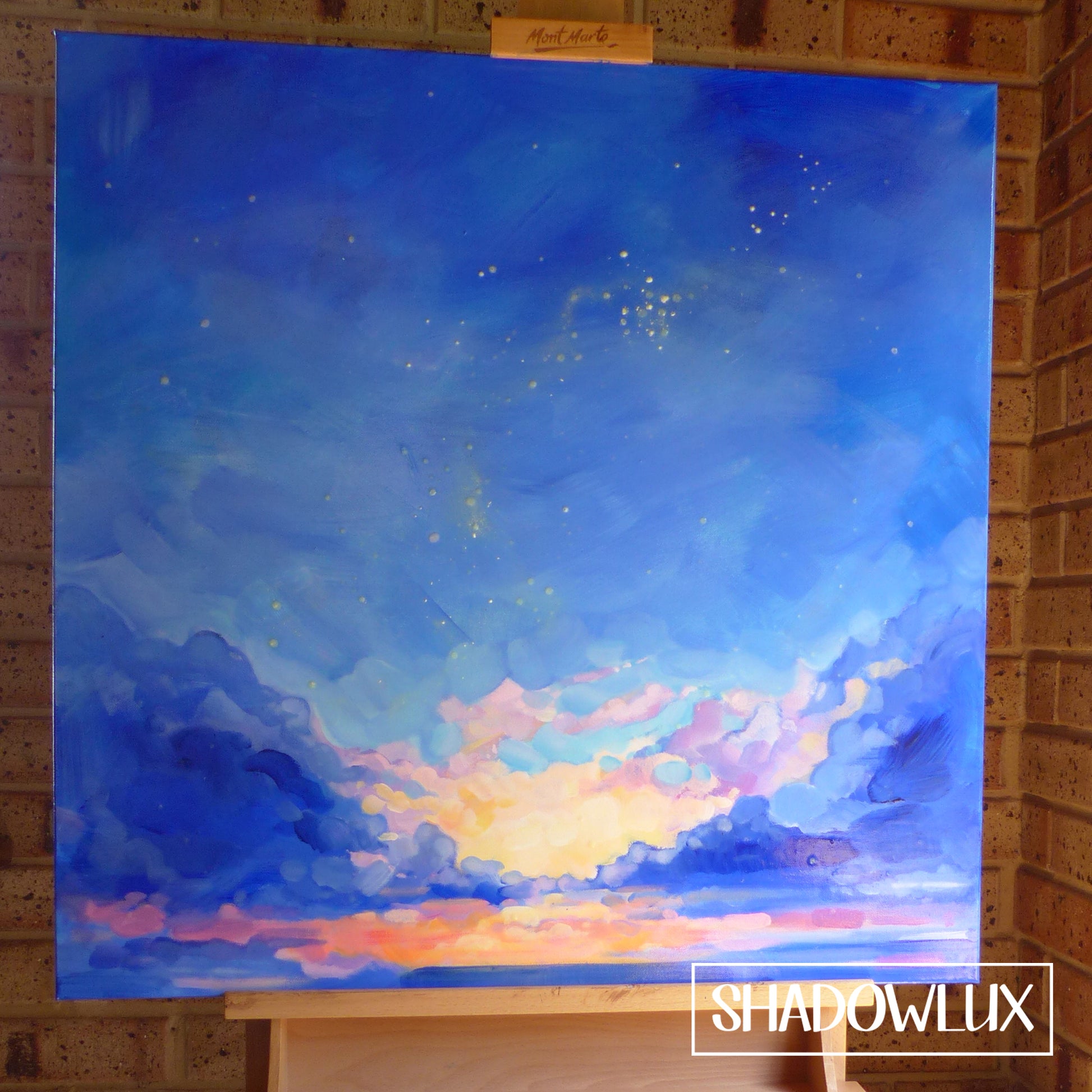 glow in the dark blue sky painting on an easel during the daytime.