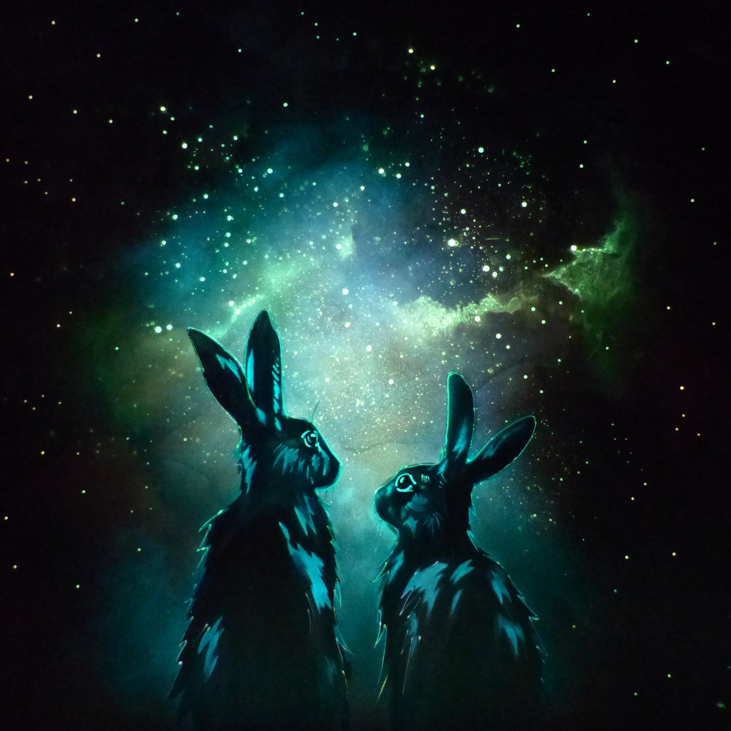 Two glow in the dark rabbits silhouetted against a starry night sky with a nebula.