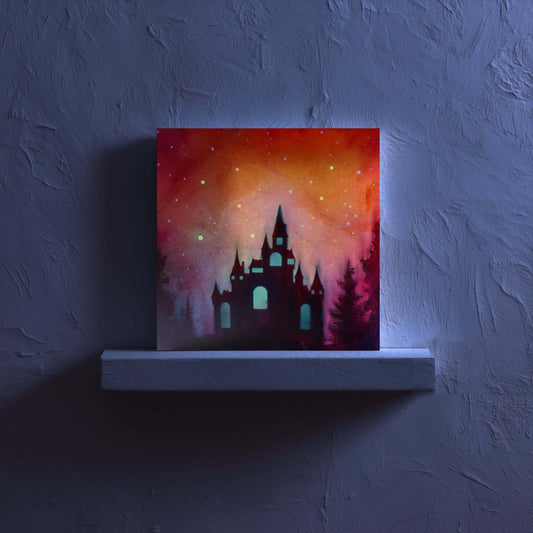 glow in the dark castle silhouette against a colorful sky on a dark wall.