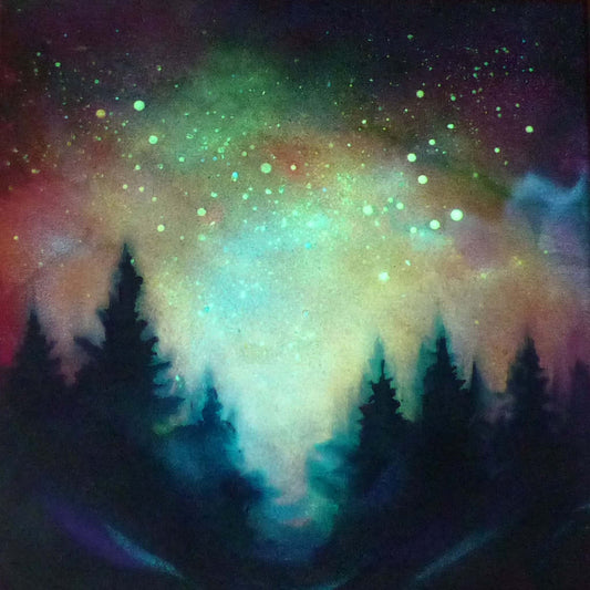 Colorful glow in the dark  nebula with silhouette of trees in the foreground