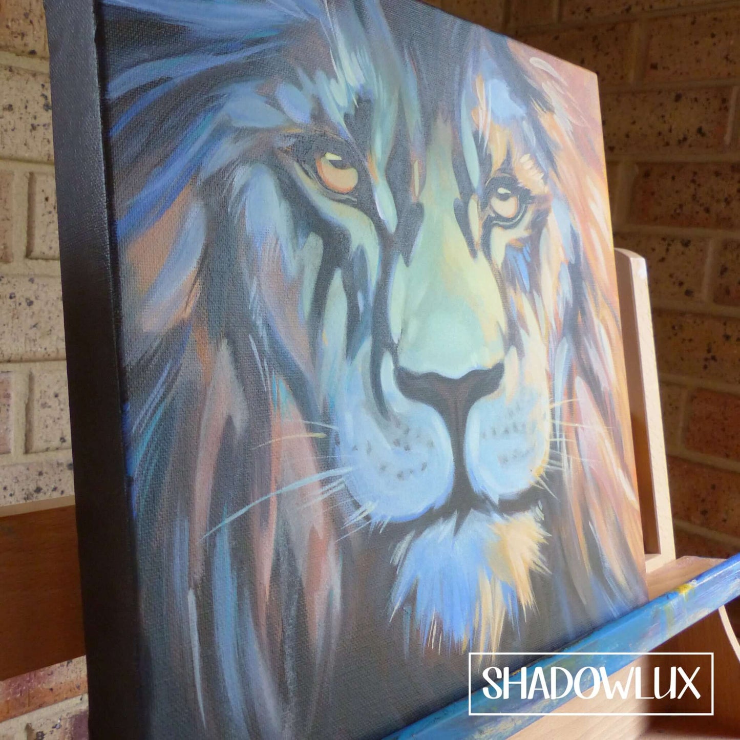 Canvas featuring a glowing lion portrait in warm colors with blue night tones, displayed on an artist’s easel