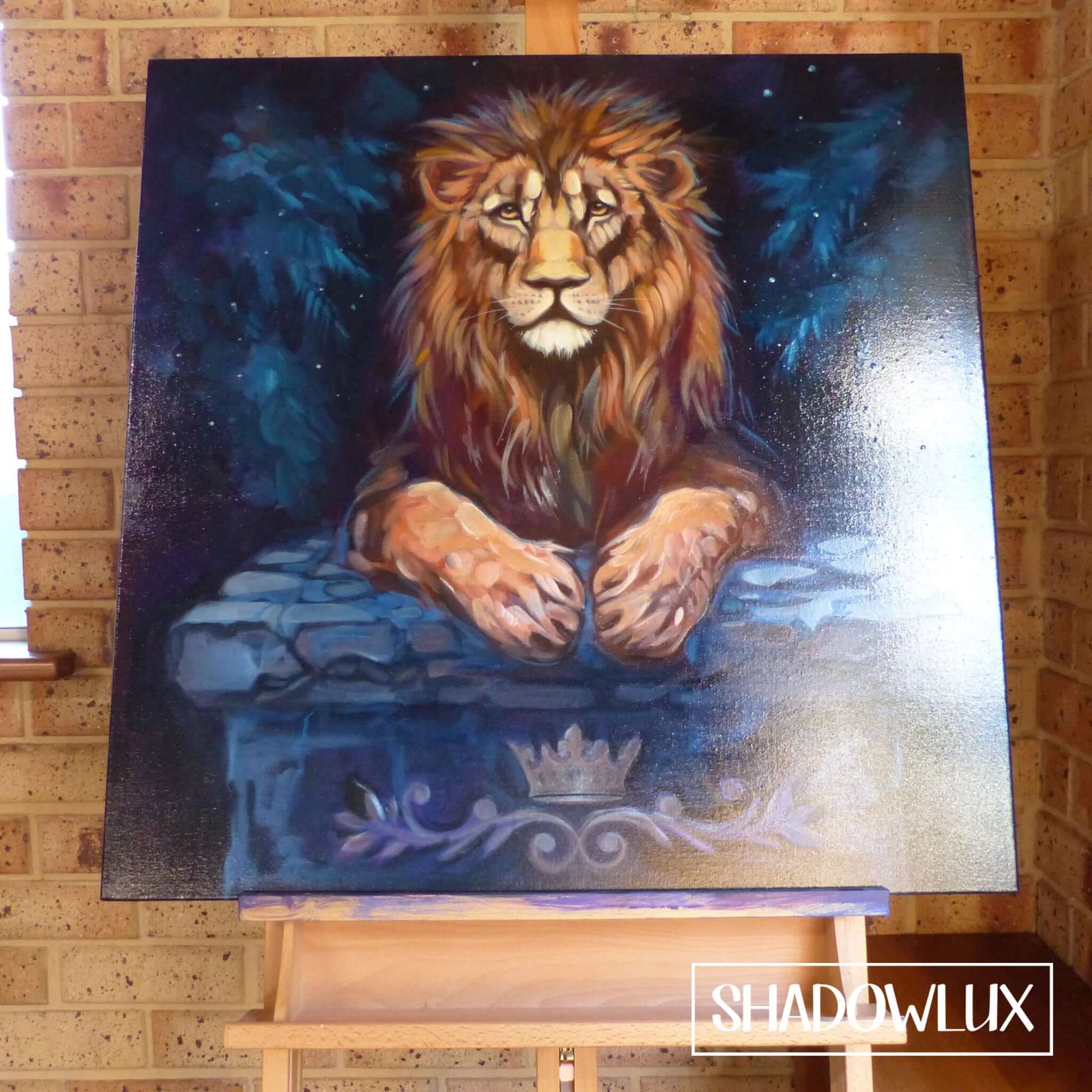 glow in the dark lion painting, lying on a blue stone table in the woods.