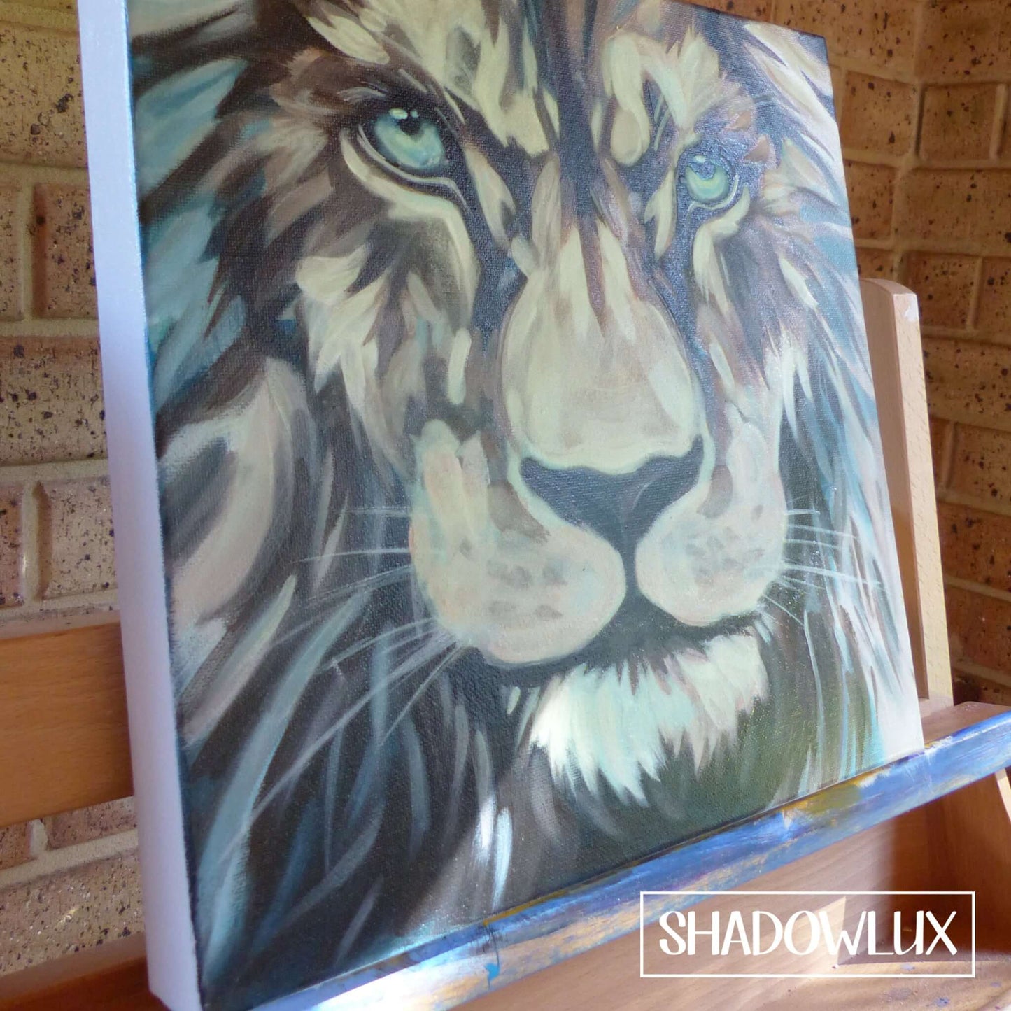 Hand-painted close-up glow in the dark portrait of a lion’s head on an easel