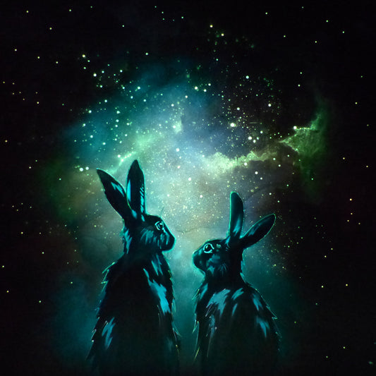 Two glow in the dark rabbits silhouetted against a starry night sky with a nebula. 