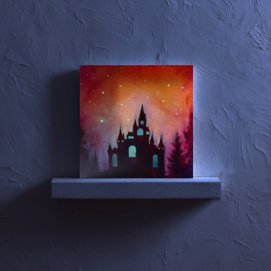 glow in the dark castle silhouette against a colorful sky on a dark wall.