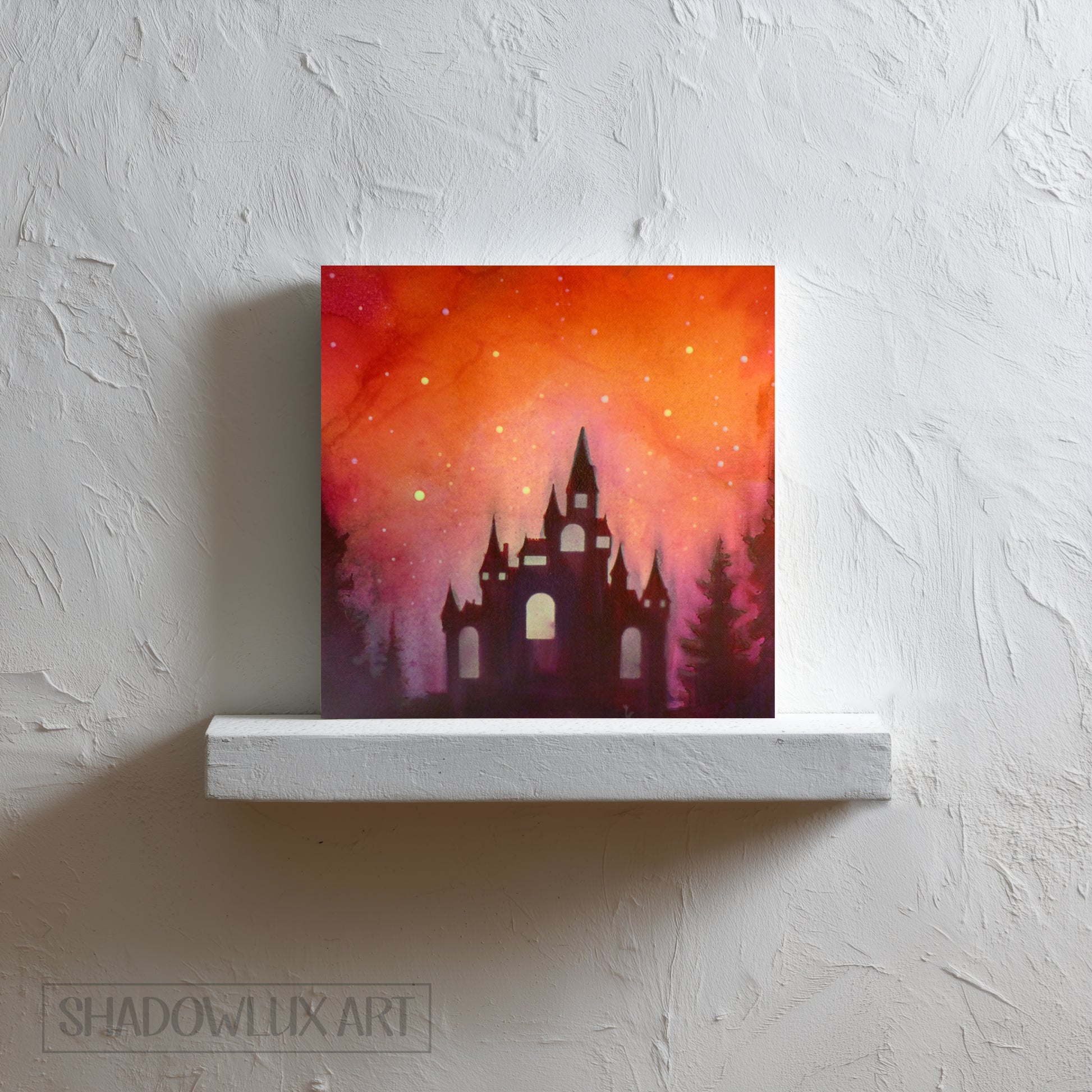 Artistic depiction of a castle silhouette against a vibrant orange and pink sky on a white shelf. 